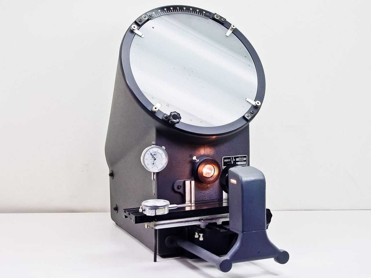 A MicroVu front illuminated optical comparator is a precision measuring instrument used to inspect and verify the dimensions of machined parts. Unlike a standard comparator that relies solely on profile lighting (backlighting), a front illuminated optical comparator uses lighting from the front of the part. This allows fine details on the surface—such as edges, engravings, or small machined features—to be seen with exceptional clarity.